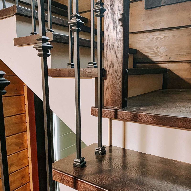 Г-образная деревянная лестница из ясеня с ковкой в брусовом доме