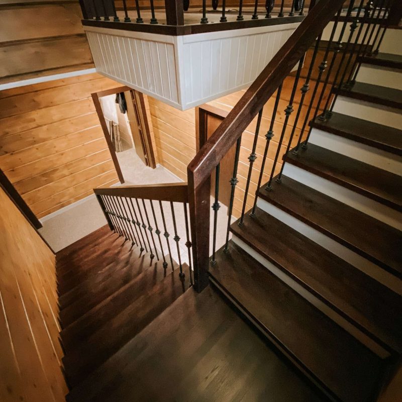 Г-образная деревянная лестница из ясеня с ковкой в брусовом доме