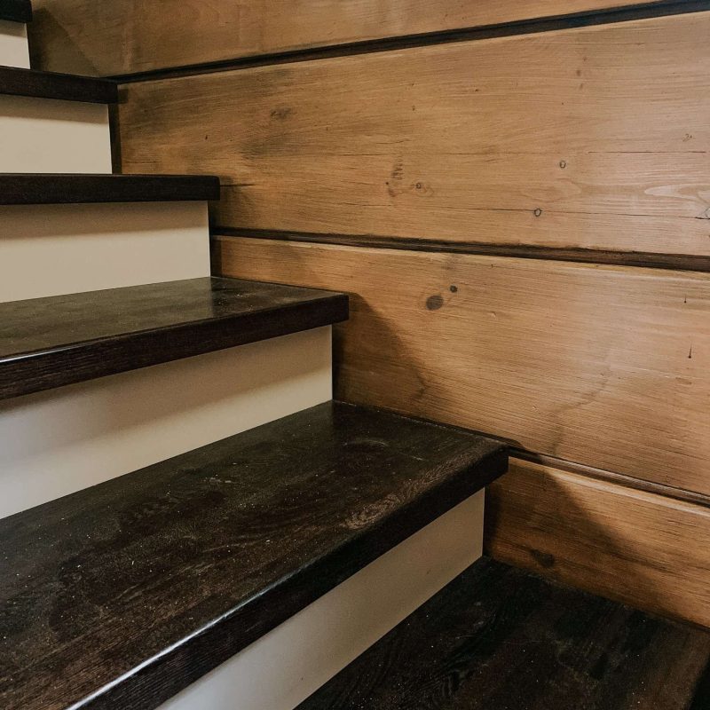 Г-образная деревянная лестница из ясеня с ковкой в брусовом доме