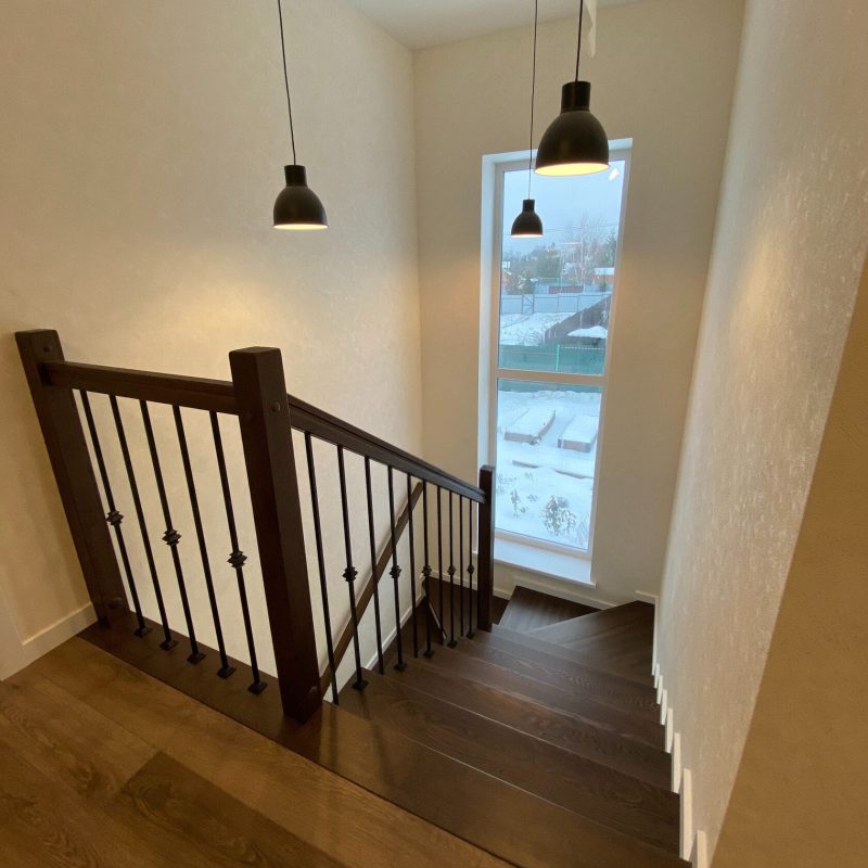 Отделка лестницы из бетона с забежными ступенями ясенем темного цвета