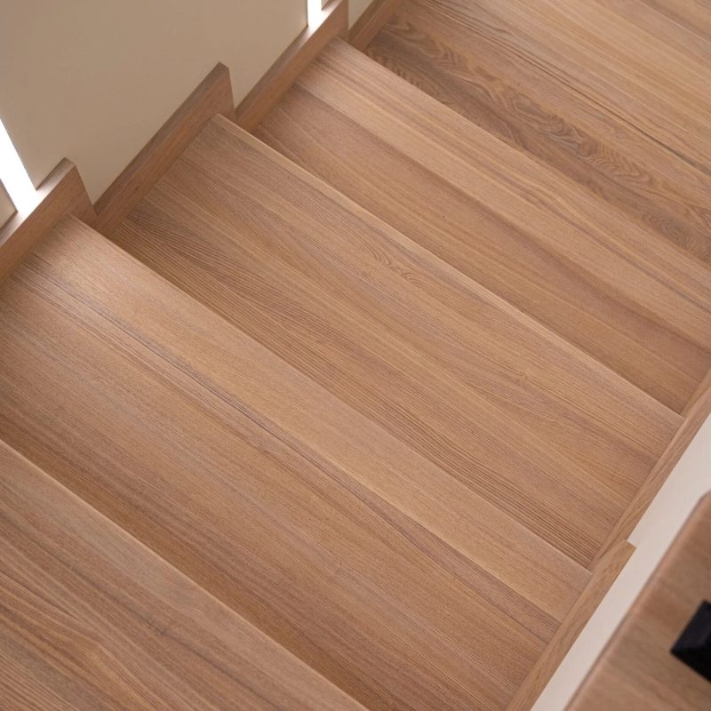 Облицовка лестницы на металлокаркасе ясенем с подсветкой на стене