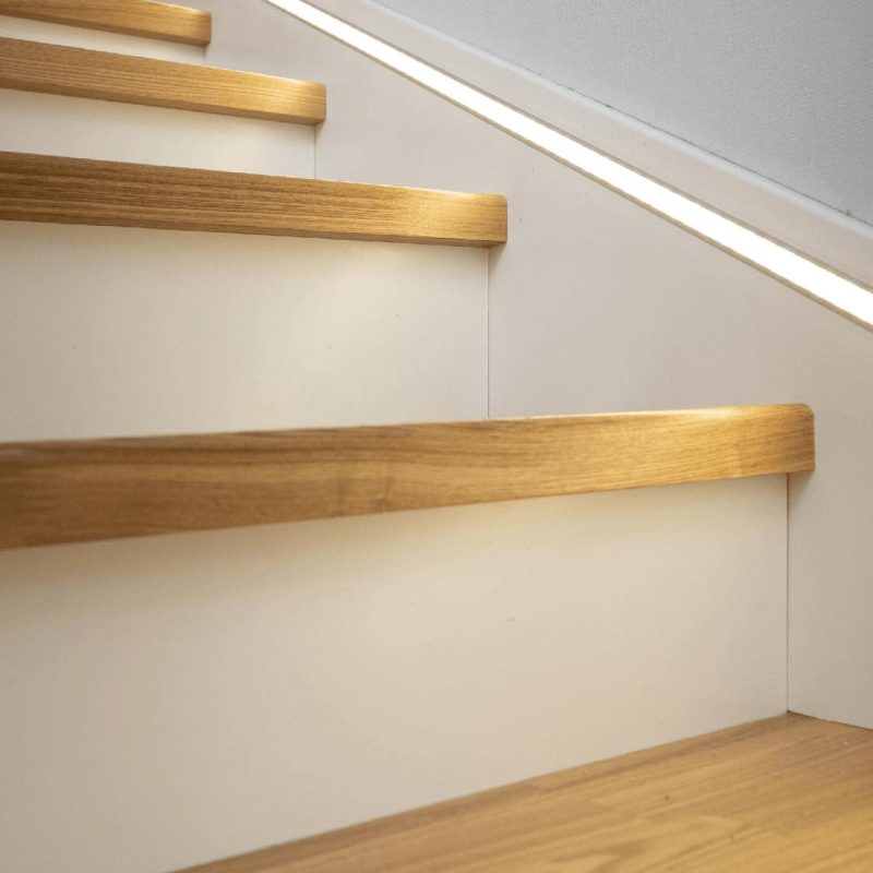 Обшивка бетонной лестницы ясенем с подсветкой в плинтусе