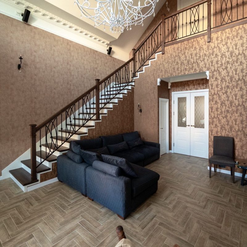 Обшивка металлокаркаса лестницы дубом с кованым ограждением