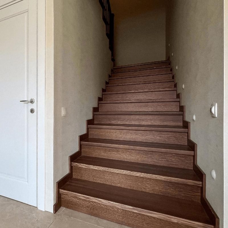 Обшивка однотонной темной бетонной лестницы ясенем